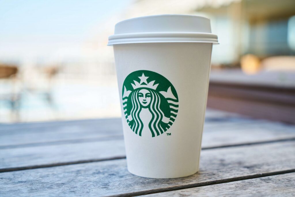 A close up view of the iconic white starbucks to go cup with their green log. 