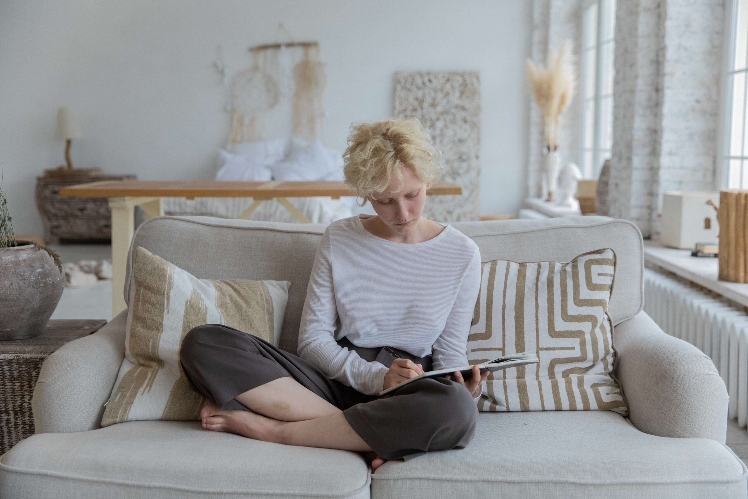 blonde haired woman on a couch writing on a pad