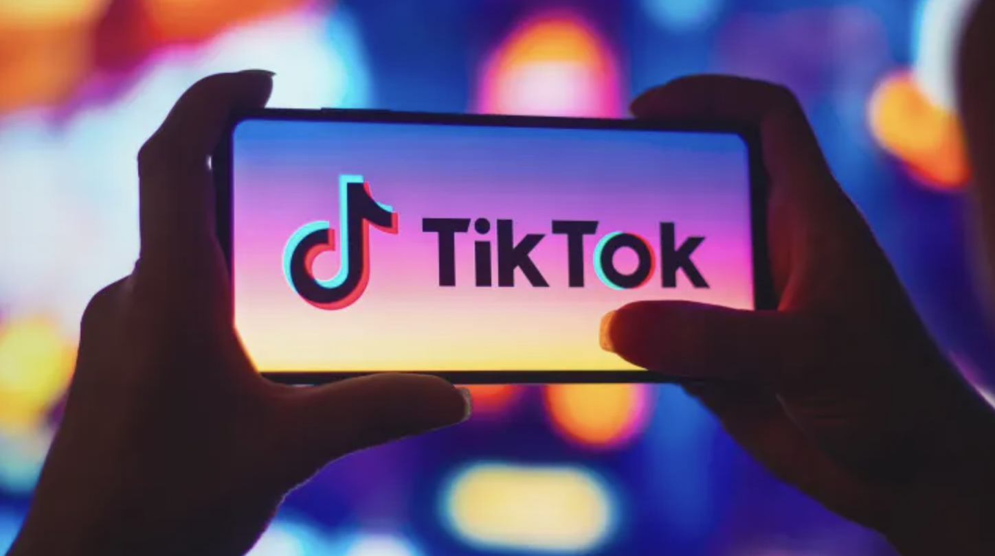 A photo of a smartphone showing the TikTok app being held in two hands