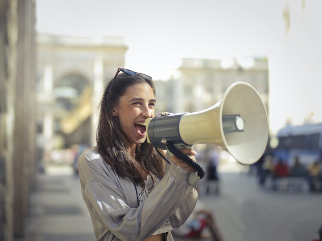 An attractive dark haired woman yelling through a louspeaker