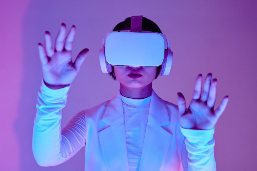 Decorative. A young woman with virtual reality goggles reaches toward the camera against a purple background.