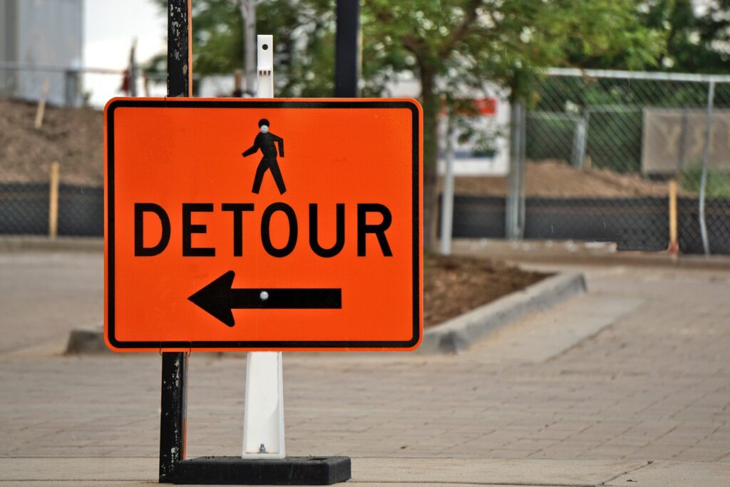 Decorative. An orange detour sign in a city. 