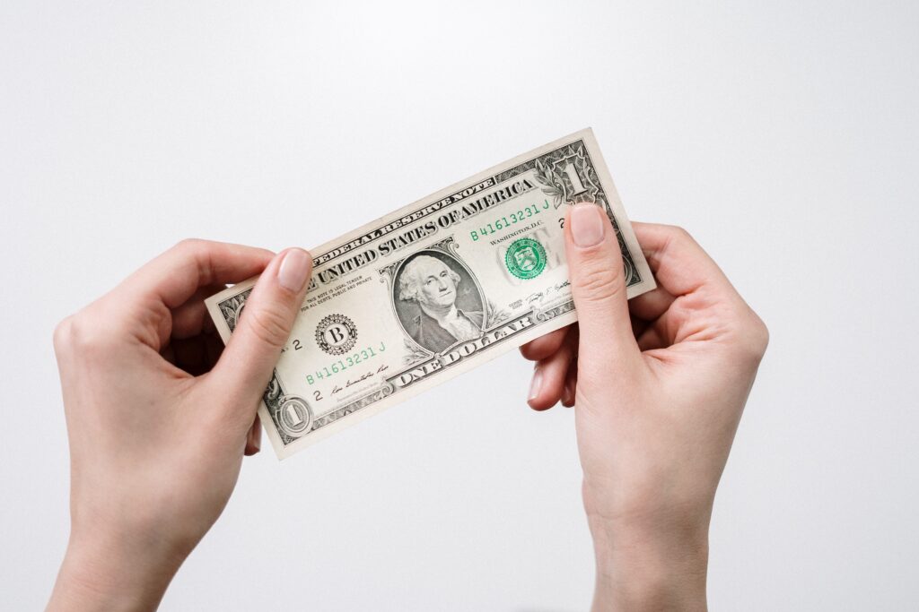 Decorative. A woman holds a one dollar bill against a white background.