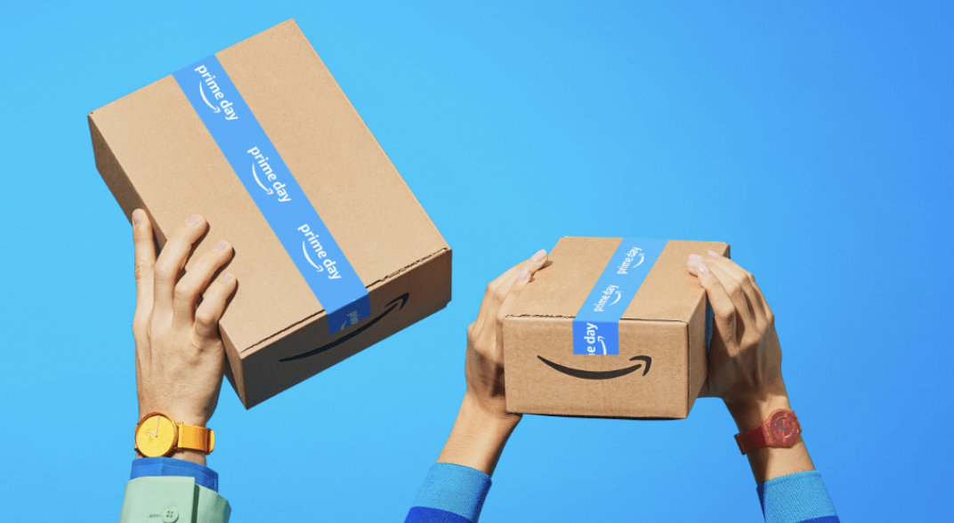 Hands holding up two Amazon packages. Two hands are on one, and one hand is holding the other