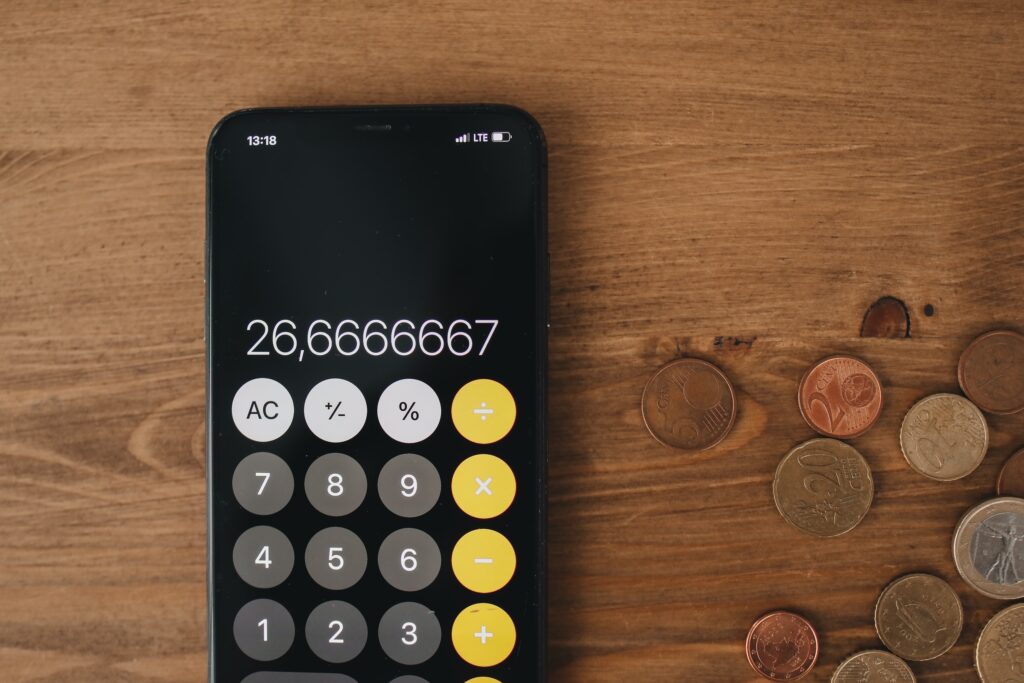 A decorative image of a calculator on a wooden table with coins scattered around