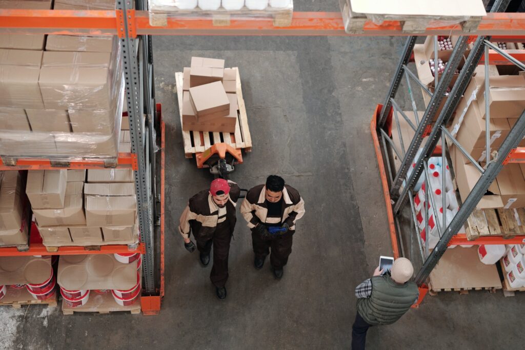 A top down view of a warehouse full of boxes and three warehouse workers 
