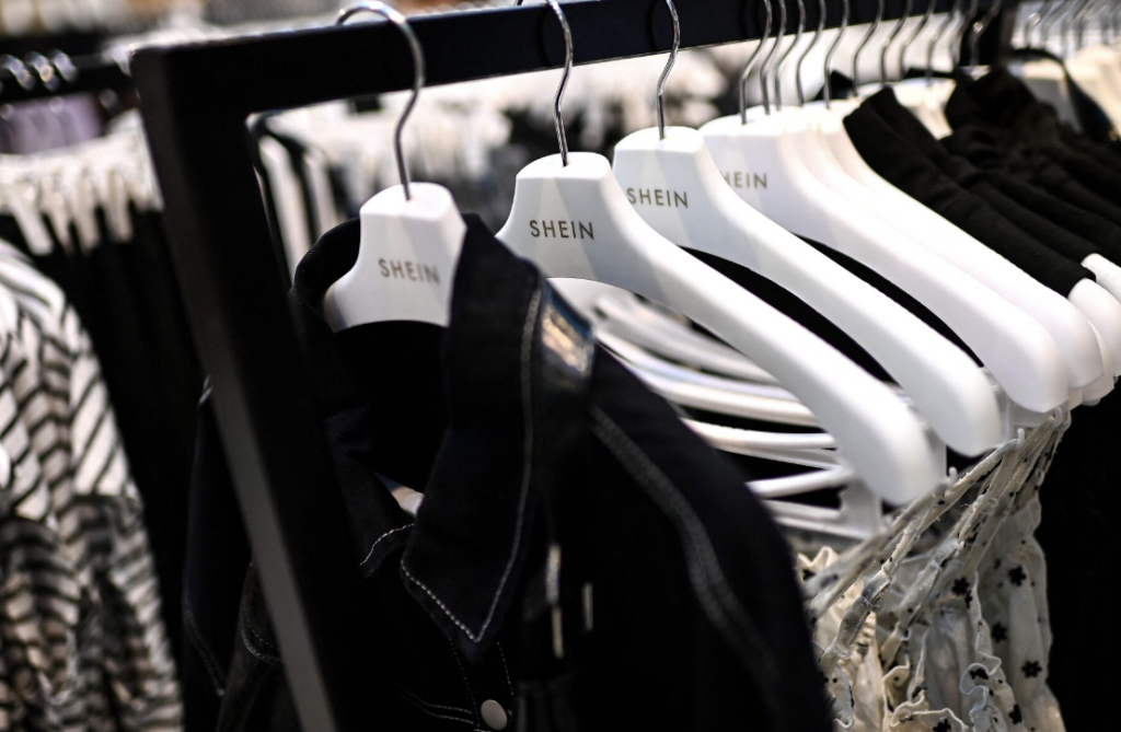 A row of Shein clothing on white Shein branded hangers on a rack in a store