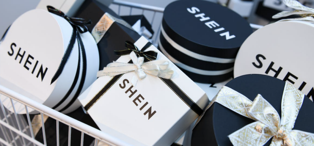 A white shopping cart full of small white and black Shein branded boxes both square and circular