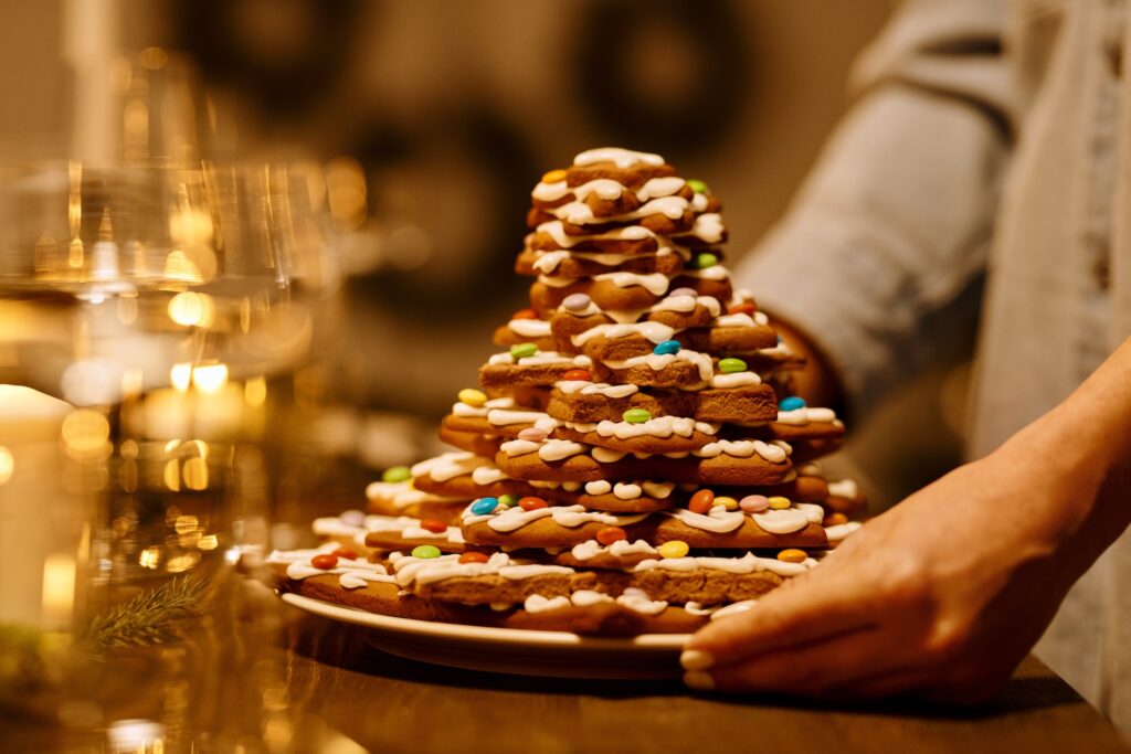 Someone serving a plate filled with holiday cookies in front of a blurred background of a festive holiday table