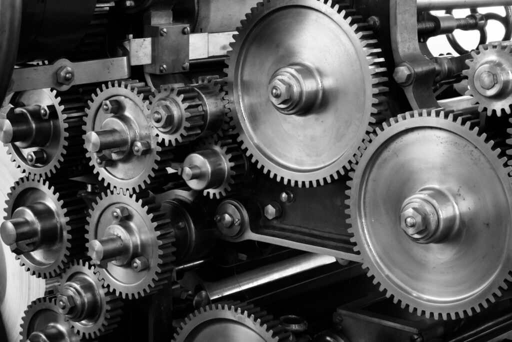 A black and white photo of a set of interconnected complicated machine gears 
