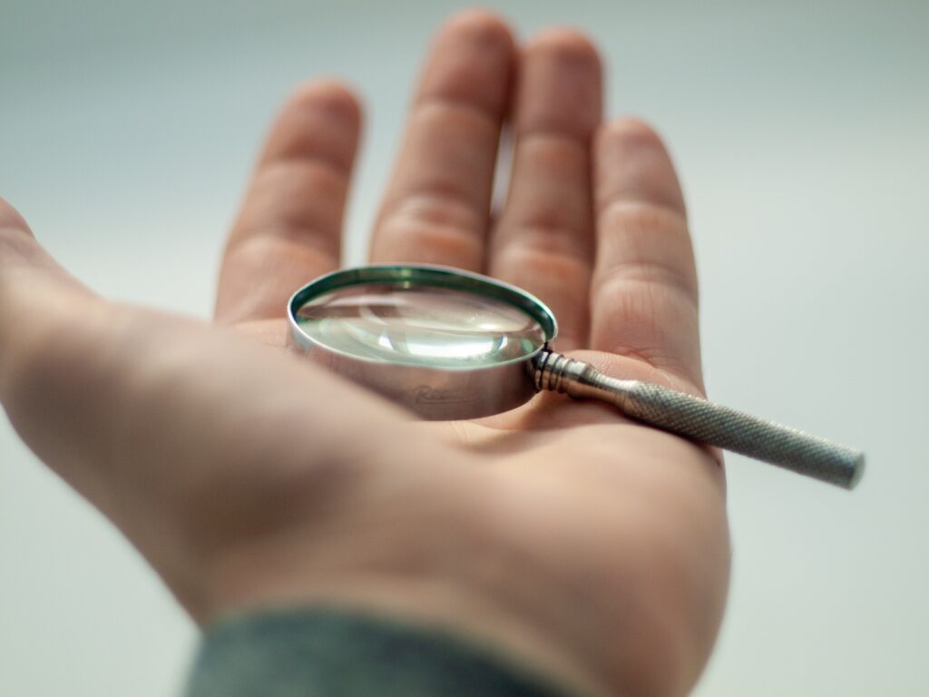 A man's left open palm holding a small magnifying glass