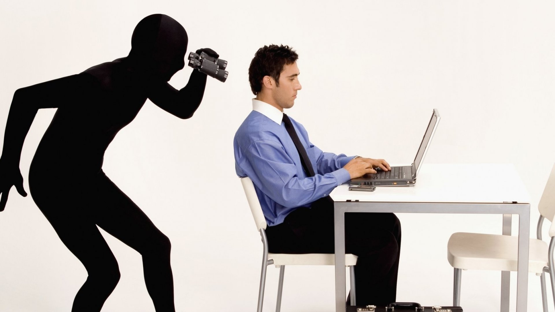 Infographic of a black shadow looking over the shoulder of a man working on a laptop