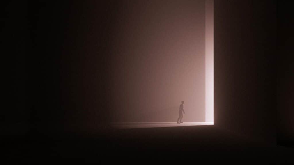 A large dark room with light streaming through a very narrow slit illuminating a man's body in profile