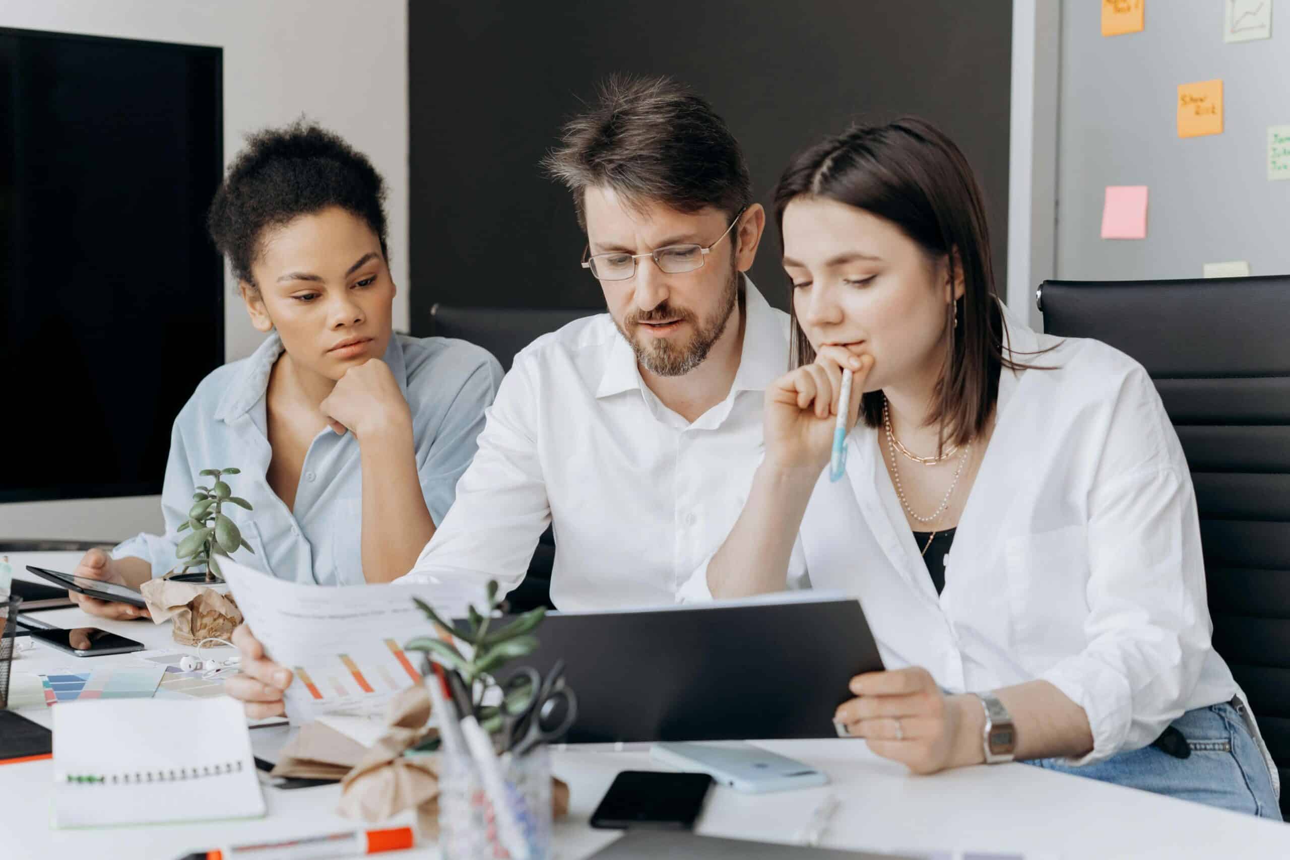 A group of 3 young ecommerce professionals, two women and a man discussing strategy at a table in a casual, stylish office